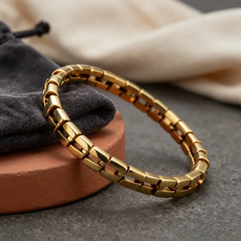 Gold bracelet links curving beside a charcoal pouch on terracotta plaster